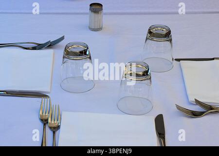 Minimalist dining table setting with white tablecloth, cutlery, glassware, ready for guests Stock Photo