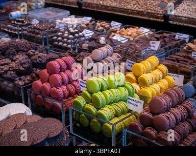 A colourful display of various flavours of French macarons for sale at a confectionery stall in La Boqueria market, Barcelona, Spain. Stock Photo