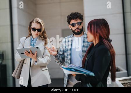 Group of diverse professionals collaborating outdoors using technology and documents Stock Photo