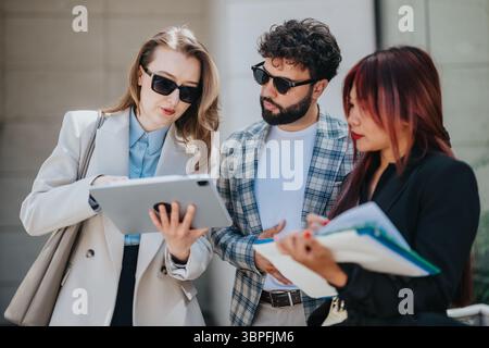 Colleagues collaborating outdoors using digital tablet and taking professional notes Stock Photo