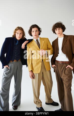 Three young men display their unique styles in a modern studio setting. Stock Photo