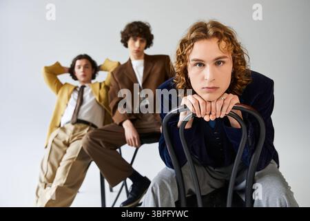 Three young men display their unique styles while posing confidently in a chic studio. Stock Photo