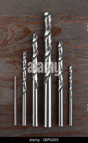 Drill bits of different sizes, on wooden background Stock Photo