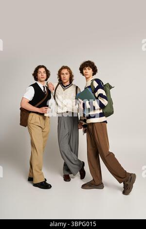 Three young men display their unique fashion sense while posing together in a vibrant space. Stock Photo