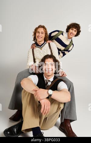 Three young men display unique styles while posing together with playful energy and camaraderie. Stock Photo