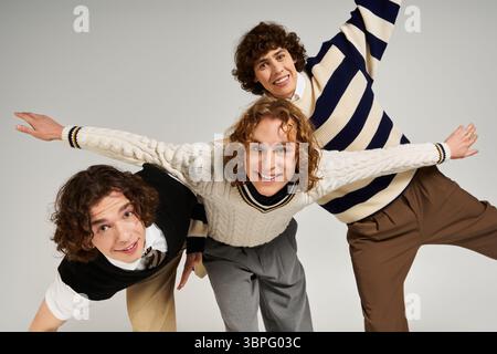 Three young men display unique styles together, exuding confidence in a creative indoor space. Stock Photo