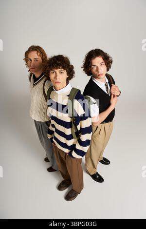 Three friends display their unique styles while posing together against a neutral backdrop. Stock Photo