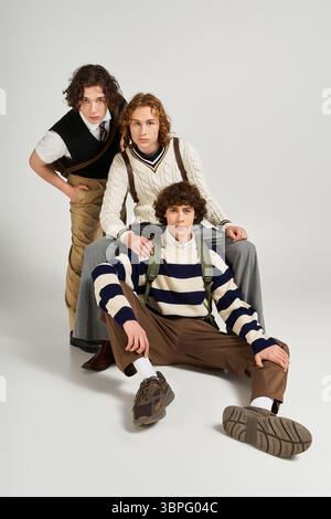 Three young men display their unique fashion styles, posing confidently in a vibrant studio. Stock Photo