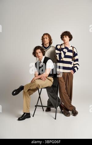 Three young men with unique styles pose playfully together, showcasing their friendship. Stock Photo