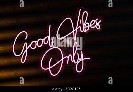 Pink neon sign displaying the inspirational message good vibes only against a dark background, promoting positivity and good energy Stock Photo