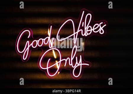 Vibrant pink neon sign displaying the words good vibes only against a dark background, creating a lively and optimistic atmosphere Stock Photo