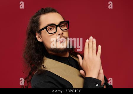 Confident young handsome man poses stylishly with hands together, showcasing charm and charisma. Stock Photo