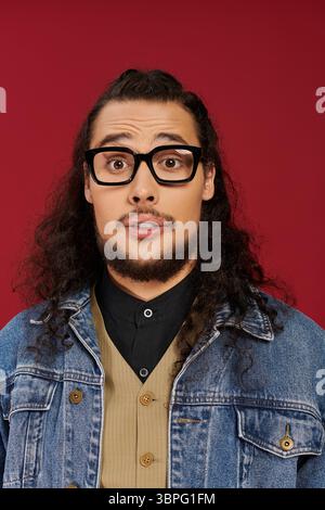 Handsome young man with curly hair and beard expresses surprise while posing for the camera. Stock Photo