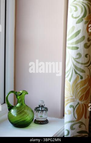 Bright window sill display with green vase and perfume bottle. Walls Little Greene, Castell Pink Stock Photo