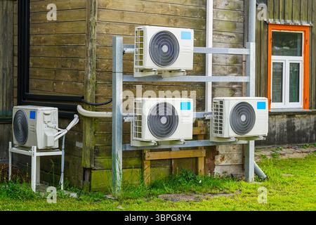 Multiple Air-to-Air Heat Pump Outdoor Units Installed on Wooden Wall of a Residential Building Stock Photo