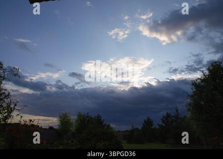 Beautiful dramatic sky with layered white and dark clouds at sunset. Natural sky background for design, weather forecast, calm, and nature themes. Stock Photo