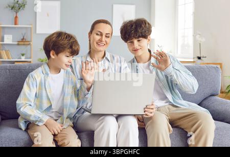 Happy Mother With Two Sons Having Online Video Call On Laptop At Home Stock Photo