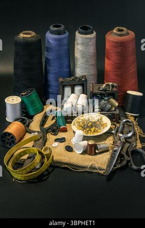 Steel scissors, Spools of thread of various colors, Thimbles in small wooden treasure chest, Sewing needles stuck in a green miniature spools thread a Stock Photo