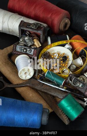 Spools of thread of various colors, Thimbles in small wooden treasure chest, Steel scissors, Sewing needles stuck in a green miniature spools thread a Stock Photo