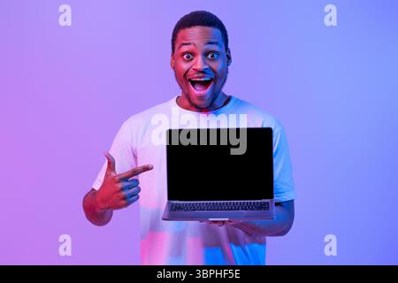Check This. Overjoyed Black Guy Pointing At Laptop Computer With Blank Screen Stock Photo