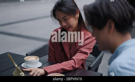 Business colleagues discussing work at outdoor cafe, using tablet and enjoying coffee Stock Photo