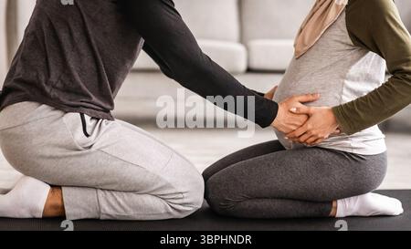 Couples Pregnancy Yoga. Cropped Shot Of Muslim Spouses Training Together At Home Stock Photo