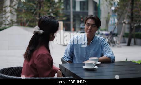 Business colleagues conversing while drinking coffee at outdoor cafe setting Stock Photo