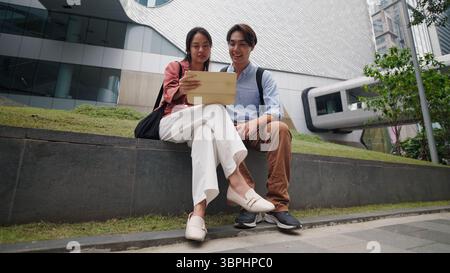 Young professionals collaborating on tablet during outdoor office break Stock Photo