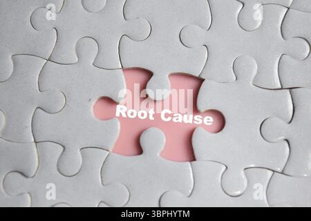 Hand holding piece of jigsaw puzzle with word Root cause. Business and finance concept Stock Photo