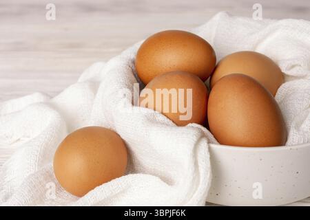 Chicken eggs in a white cup with a cotton napkin, close-up Stock Photo