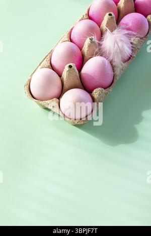 Minimal Easter concept. Easter elements, paper box with eggs in pink colors on pastel green background. Copy space Stock Photo
