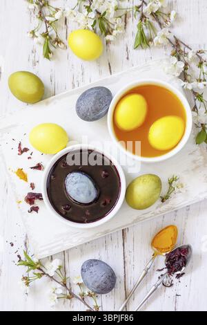 Natural dye for easter eggs, celebration Easter. Homemade colored easter eggs in carcade and turmeric on a rustic table. Top view flat lay Stock Photo