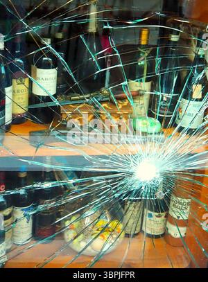 Broken wine shop window in Milan, Italy, with vintage Barolo bottles on display Stock Photo