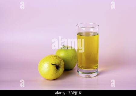 Two green apples and a glass of apple juice on a pink background, copy space Stock Photo