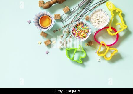 Baking or cooking background. Ingredients for Easter festive baking. Kitchen utensils, flour, brown sugar, eggs and butter on a light green background Stock Photo