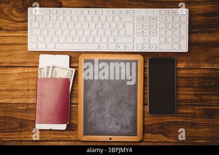 Flat top-down view showing chalkboard slate between keyboard, passport, US dollar bills, smartphone Stock Photo