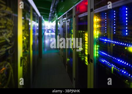 Server rack on right side is showing blinking LED panels in flat design corridor under cables Stock Photo