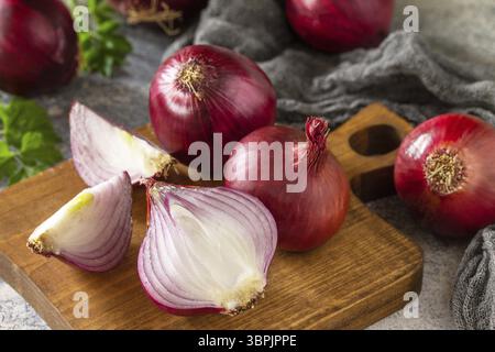 Purple Onions. Fresh whole purple onions and one sliced onion on a stone countertop Stock Photo