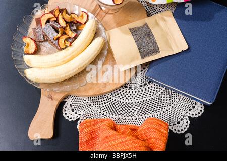 Bananas, dried apples, lavender, and a blue book on a decorative tablecloth. Stock Photo