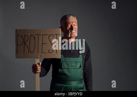 Protesting miner man with placard on dark background Stock Photo