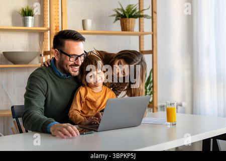 Happy family with kids having fun using laptop together, parent and children relaxing at home Stock Photo