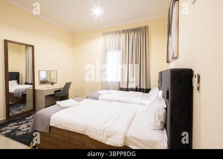 A comfortable townhouse bedroom with two twin beds, featuring modern interior design and warm lighting. Stock Photo