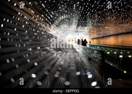 National Gallery Of Art Multiverse Light Installation Washington DC | WASHINGTON D.C., United States — Visitors walk through Multiverse, Leo Villareal's LED light installation in the Concourse connecting the National Gallery of Art's East and West Buildings. Created in 2008, the 200-foot (61 m) tunnel contains roughly 41,000 computer-programmed LED nodes that generate patterns rarely repeated. Villareal, a Yale- and NYU-trained artist, is known for large-scale light-based works using custom software. Stock Photo