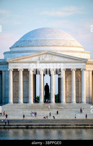 Jefferson Memorial Western Facade Seen From Across Tidal Basin in Washington DC | WASHINGTON DC — The Jefferson Memorial's domed rotunda and Ionic colonnade are reflected in the Tidal Basin in this view of the memorial's western side. The north pediment sculpture by Adolph Alexander Weinman — depicting Thomas Jefferson and the four other members of the Committee of Five who drafted the Declaration of Independence in 1776 — is visible above the north entrance portico. Designed by John Russell Pope and completed after his death by partners Otto R. Eggers and Daniel P. Higgins, the circular colon Stock Photo