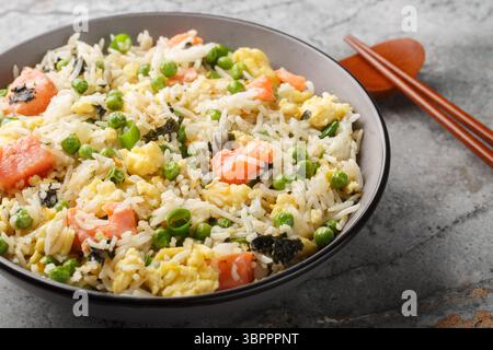 Salmon fried rice with egg, seaweed and vegetables close-up on bowl on the table. Horizontal Stock Photo