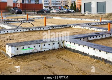 Modern building foundation under construction with insulated forms, utility pipes, structural layout Stock Photo