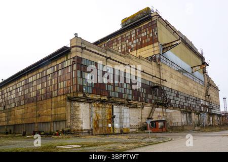 Abandoned factory with rusty metal panels and weathered concrete exterior Stock Photo