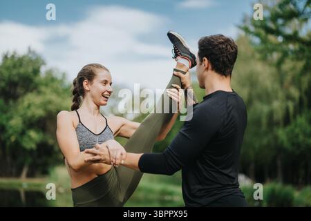 Partners practicing fitness and flexibility exercises in a park with lush greenery under a clear blue sky Stock Photo