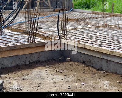 A concrete foundation slab with steel reinforcement bars or rebar at construction site Stock Photo