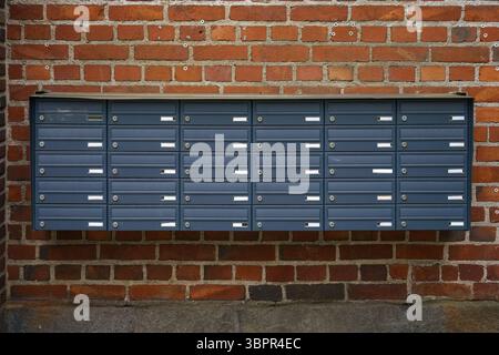 Row of metallic mailboxes mounted on a historic red brick wall Stock Photo